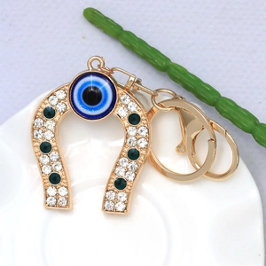 Detail of golden horseshoe keychain with blue evil eye and sparkling rhinestones