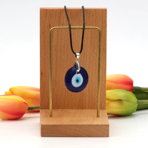 Evil eye glass pendant necklace with black wax rope displayed on a wooden stand