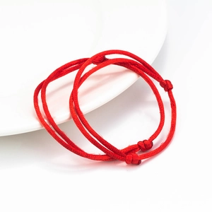 Handmade lucky red rope bracelets for couples on a white plate with adjustable knots