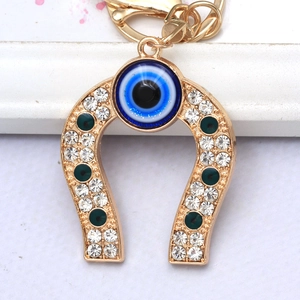 Detailed view of golden horseshoe keychain featuring blue evil eye and sparkling rhinestones