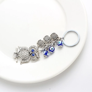 Détail d'un porte-clés chouette rétro avec perles œil bleu sur fond de porcelaine blanche