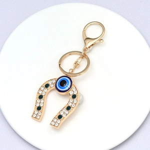 Macro detail of horseshoe keychain with blue evil eye bead and sparkling crystals