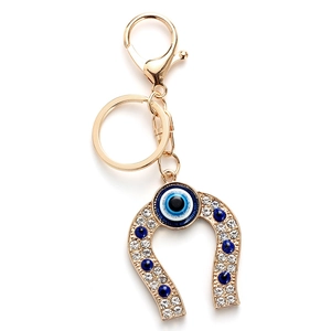 Golden horseshoe keychain with evil eye charm and sparkling white crystal inlay