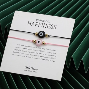 Detailansicht von rosa und schwarzen Evil Eye Armbändern mit Goldperlen auf Displaykarte