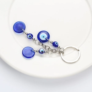 Blue Turkish Evil Eye keychain with glass beads and silver alloy ring on a white plate
