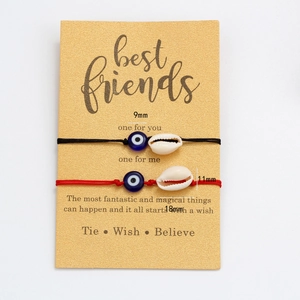 Detail von roten und schwarzen Evil-Eye-Armbändern mit Muscheln auf Geschenkkarten