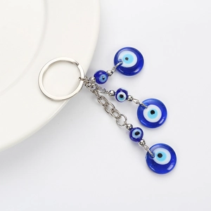Blue glass evil eye keychain with silver chains and beads on a white surface