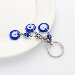 Blue glass Evil Eye keychain with silver alloy chain on a white plate