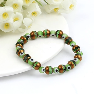 Detail of beaded Evil Eye bracelet with brown and green beads on a white plate