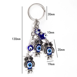 Detailed view of Evil Eye owl keychain charms in silver alloy with blue bead accents