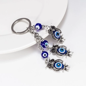 Macro view of vintage silver owl charms with blue evil eye beads on keychain