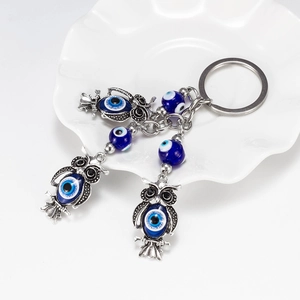 Detail of vintage silver owl key ring with blue evil eye beads in a ceramic tray