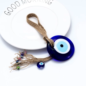 Macro detail of hand-woven hemp rope with blue evil eye glass bead and colorful accents