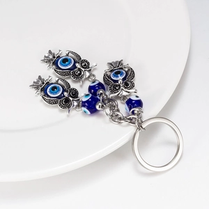 Detail view of silver owl evil eye keychain pendant with blue beads and metal ring