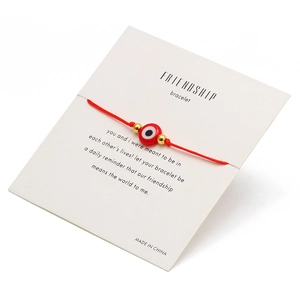 Detail eines roten Evil Eye Freundschaftsarmbands mit Goldperlen auf Geschenkkarte