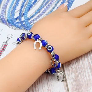 Détail des perles bleues de l'œil maléfique et breloques fer à cheval sur le bracelet élastique