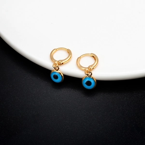 Golden hoop earrings with blue Evil Eye charms displayed on a stylish black and white surface