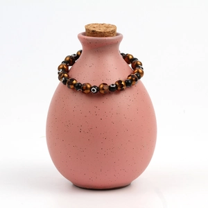 Bohemian evil eye beaded bracelet with leopard print and black stones on a pink vase