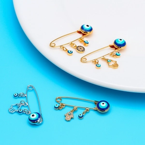 Lucky Evil Eye and Hamsa Hand safety pin brooches set with blue charms in gold and silver
