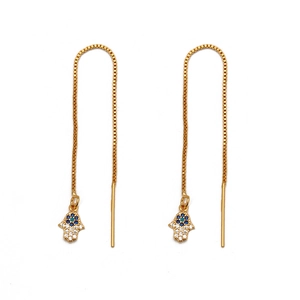 Macro detail of gold Hamsa hand earrings with blue evil eye and sparkling zircon stones