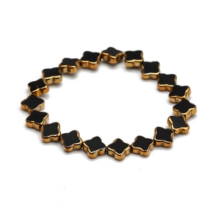 Détails de trèfles à quatre feuilles noirs et dorés sur un bracelet élastique perlé