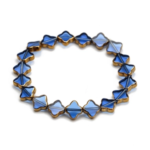 Détail macro de perles trèfles en cristal bleu avec bords dorés sur bracelet élastique