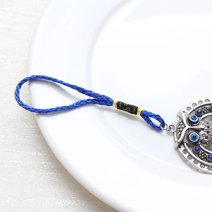 Detail shot of vintage silver owl keychain with evil eye charm on white ceramic