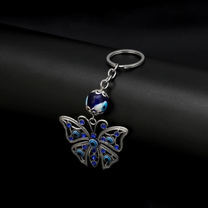 Exotic evil eye butterfly keychain with blue rhinestones on a dark polished background