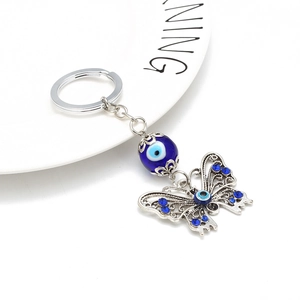 Detailed view of evil eye butterfly keychain with blue rhinestones on white ceramic