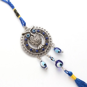 Detail of silver owl charm with blue evil eye beads and a long silk tassel hanging