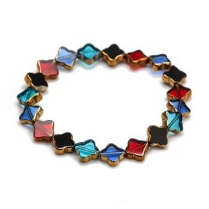 Détail des perles trèfle colorées en bleu et rouge avec bordure dorée pour ce bracelet