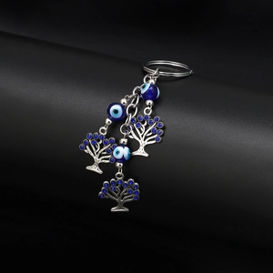 Detailed close-up of lucky evil eye keychain with silver metal tree charms and blue beads