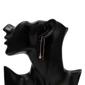 Detailed view of gold Hamsa hand earrings with blue evil eye on a model ear