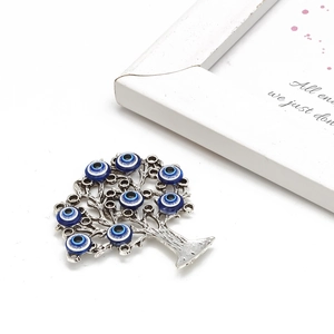 Silver Tree of Life ornament with blue Evil Eye charms on a white decorative background
