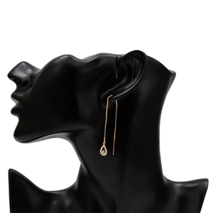 Detail of long gold evil eye threader earrings on black mannequin display