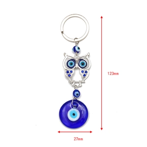 Detailed macro view of an alloy owl evil eye keychain with blue rhinestones and glass pendant