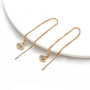 Golden Evil Eye threader earrings with blue charms and zircons on a white ceramic plate