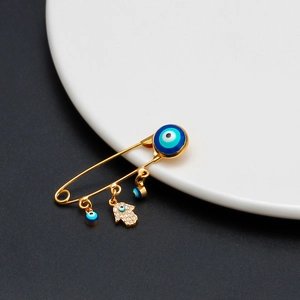 Macro detail of gold evil eye hamsa brooch with sparkling crystals on a white ceramic plate