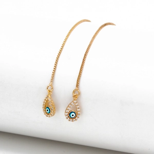 Macro shot of gold-plated evil eye drop earrings with white zircon on a white stand