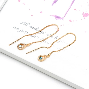 Detail of gold evil eye threader earrings with blue enamel teardrop and white zircons