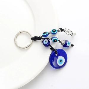 Détail du pendentif œil bleu en verre avec corde tressée et trèfle à quatre feuilles