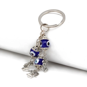 Macro shot of silver palm tree charms with blue evil eye beads on a triple chain keychain