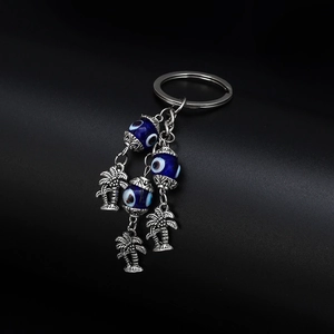 Detail of silver palm tree charms and blue Nazar glass beads on an evil eye keychain