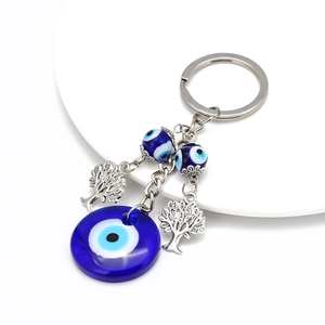 Detail of blue evil eye keychain with silver Tree of Life charms on white display