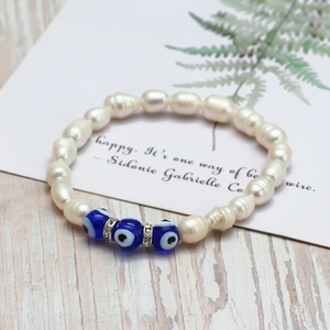 Détail du bracelet en perles d'eau douce avec perles oeil bleu et anneaux brillants