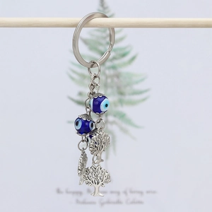Close-up of Evil Eye and Tree of Life charms on a silver metal keychain with blue beads