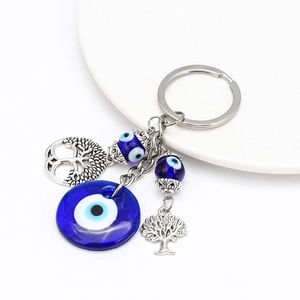 Detailed view of evil eye glass pendant with silver tree of life charms on keychain
