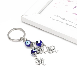 Detailed view of evil eye beads and Tree of Life charms on a silver keychain with card