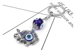 Detailed close-up of antique silver elephant keychain with blue evil eye bead and rhinestones