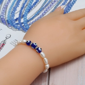 Détail macro du bracelet en perles d'eau douce avec yeux bleus et séparateurs en cristal